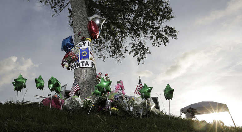 Television newscasters prepare to give updates near a memorial in front of Santa Fe High School on Sunday, May 20, 2018 in Santa Fe, Texas, where a student shot and killed eight classmates and two teachers at Santa Fe High School. Television newscasters prepare to give updates near a memorial in front of Santa Fe High School on Sunday, May 20, 2018 in Santa Fe, Texas, where a student shot and killed eight classmates and two teachers at Santa Fe High School.