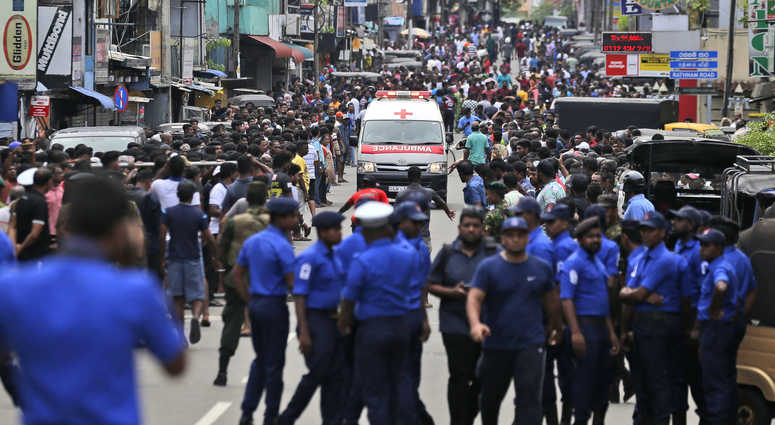 Sri Lankan police officers clear the road as an ambulance drives through carrying injured of Church blasts in Colombo, Sri Lanka, Sunday, April 21, 2019. Sri Lankan