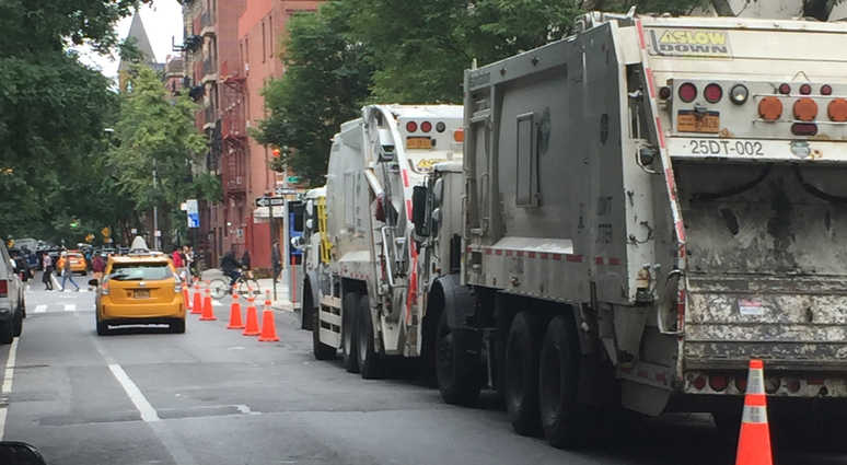 Garbage trucks parked along a road in the East Village Garbage trucks