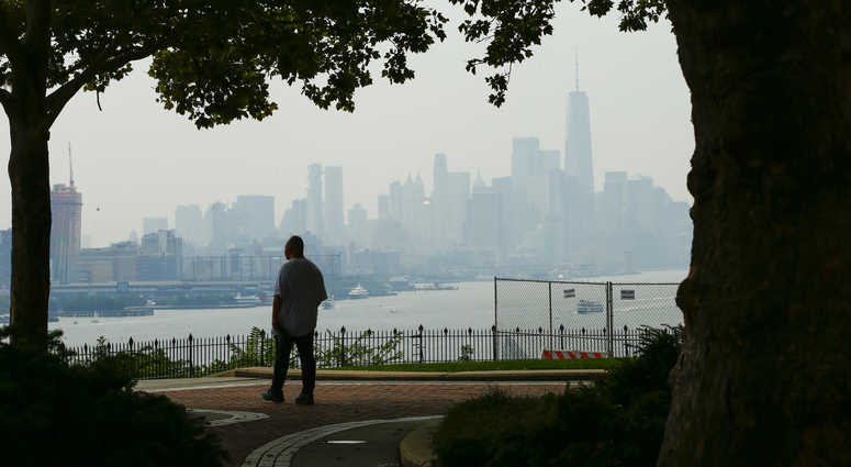 A man takes a look of the haze over the New York skyline and One World Trade Center on August 17, 2018 in Weehawken, New Jersey. Severe thunderstorms and even an isolated tornado could strike New York City on Friday. New York City skyline
