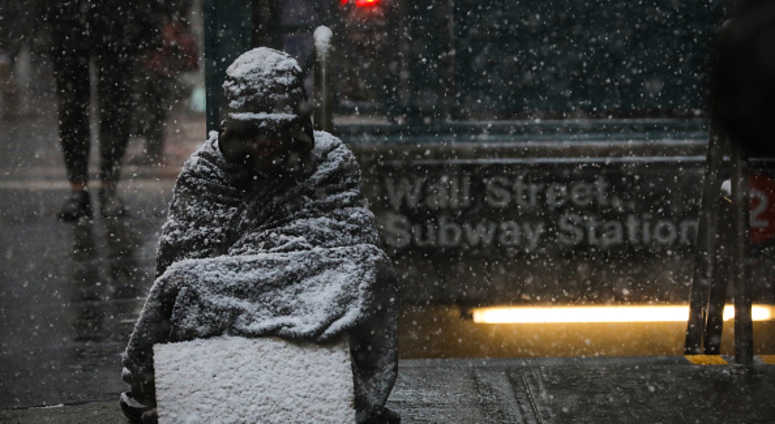A homeless man sits in the falling snow in the Financial District, January 30, 2019 in New York City. A homeless man sits in the falling snow in the Financial District, January 30, 2019 in New York City.