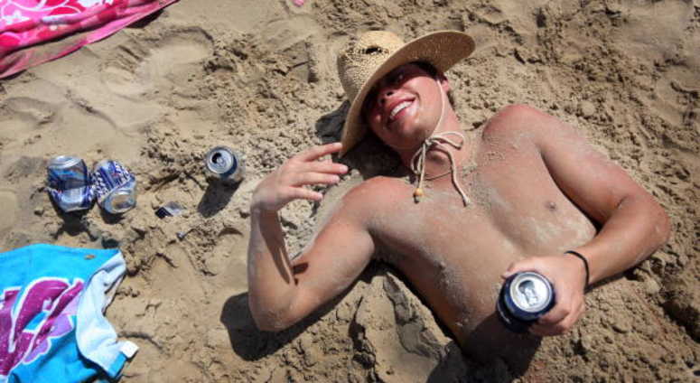 A drunken student lies half buried in sand on the beach during the annual ritual of Spring Break Spring Break South Padre Island