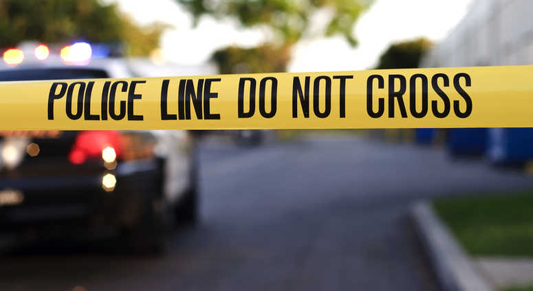 Yellow police tape at a crime scene with a police car in the background. police tape