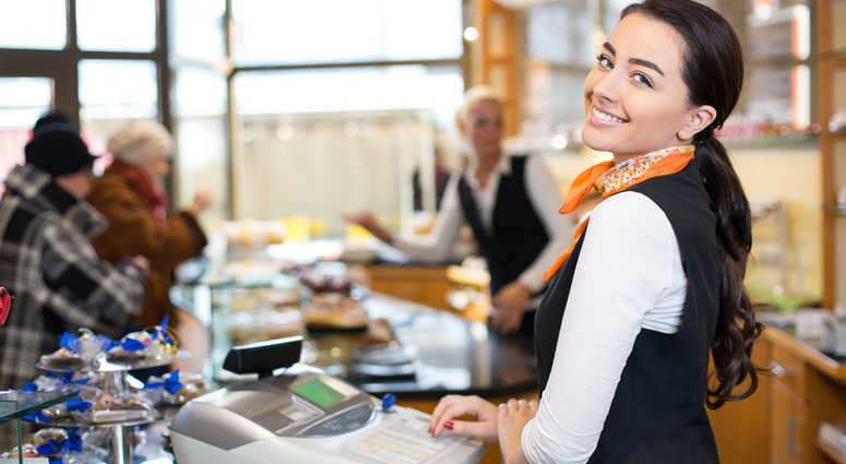 A young woman working the cash register in a shop. Cashier