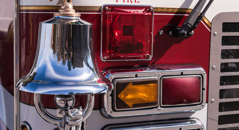 Bright chrome and brass bell on the front of a fire truck and front lights. Bright chrome and brass bell on the front of a fire truck and front lights.