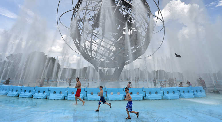 Children plays in the Unisphere fountain to cool of from temperatures approaching 100 degrees fahrenheit, with “feels like” temperature of 110 degrees, in Flushing Meadows-Corona Park in the New York City borough of Queens. 2019 heat wave