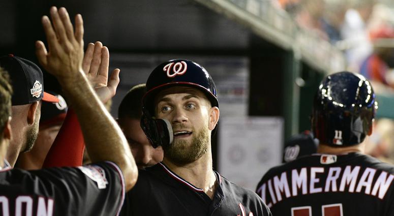 Bryce Harper celebrates with teammates in the dugout. Bryce_Harper_Mets