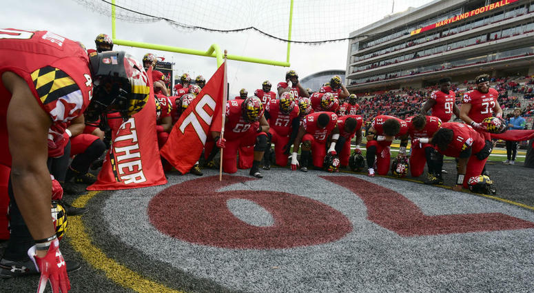Maryland players take a knee before a game. Maryland_Football_Players