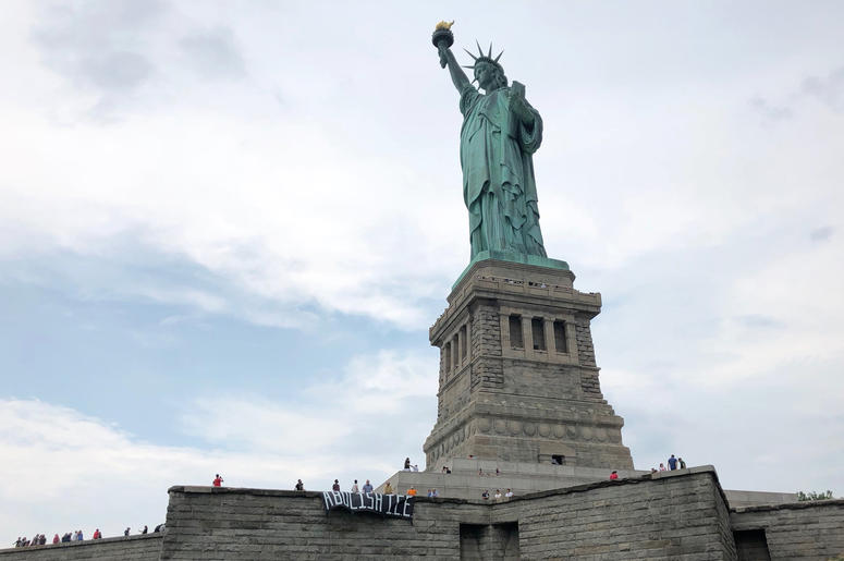 En esta fotografía difundida por el grupo Rise and Resist, varios manifestantes despliegan una carta que pide abolir el Servicio de Control de Inmigración y Aduanas de Estados Unidos (ICE por sus siglas en inglés) en la base de la Estatua de la Libertad. En esta fotografía difundida por el grupo Rise and Resist, varios manifestantes despliegan una carta que pide abolir el Servicio de Control de Inmigración y Aduanas de Estados Unidos (ICE por sus siglas en inglés) en la base de la Estatua de la Libertad.