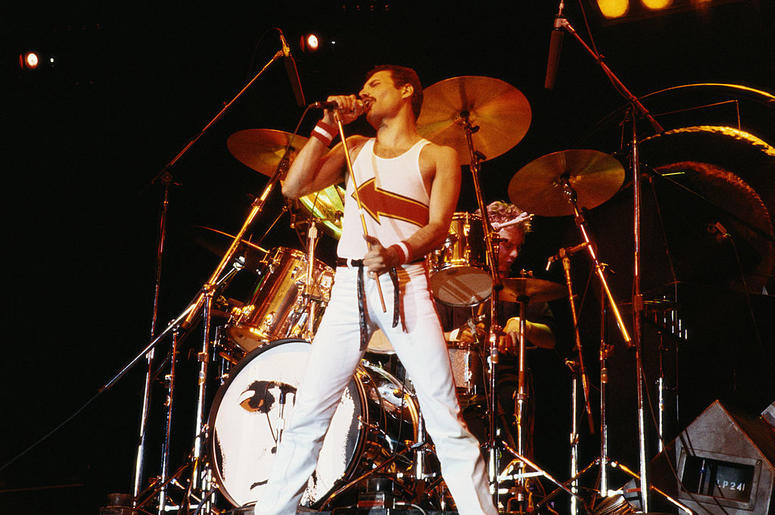 Freddie Mercury (1946-1991), singer with Queen, standing in front of a drumkit as he sings into a microphone on stage during a live concert performance by the band at the National Bowl in Milton Keynes, England, United Kingdom, on 5 June 1982. Freddie Mercury (1946-1991), singer with Queen, standing in front of a drumkit as he sings into a microphone on stage during a live concert performance by the band at the National Bowl in Milton Keynes, England, United Kingdom, on 5 June 1982.