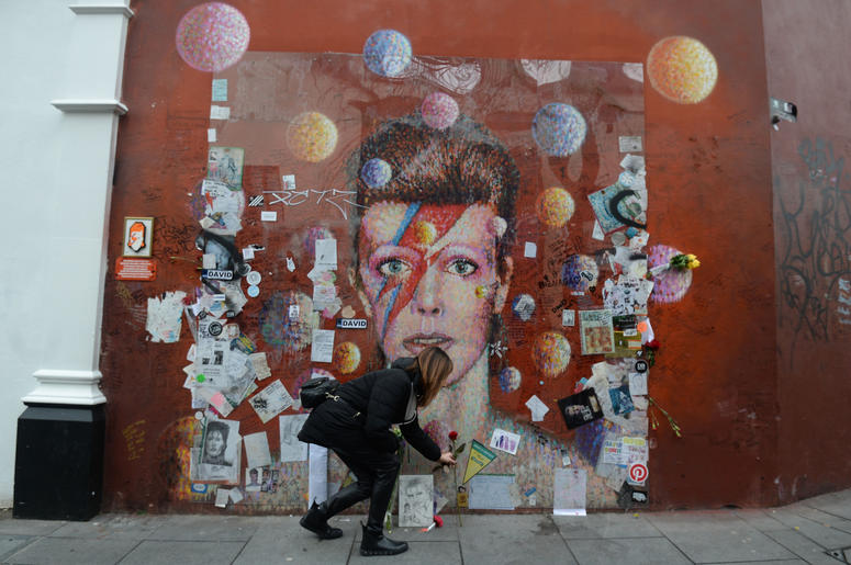 A woman lays a rose at a mural of David Bowie in Brixton, London on the second anniversary of his death. A woman lays a rose at a mural of David Bowie in Brixton, London on the second anniversary of his death.