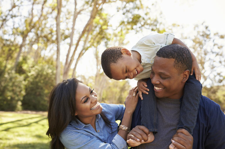 Celebrate Dad at Daddy Walk. Dad carries son on his back and mother smiles by his side.