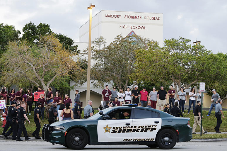 A police car drives near Marjory Stoneman Douglas High School in Parkland, Fla. Marjory_Stoneman_Douglas_Parkland_School_Shooting_Victims_Sue_School_Sheriff