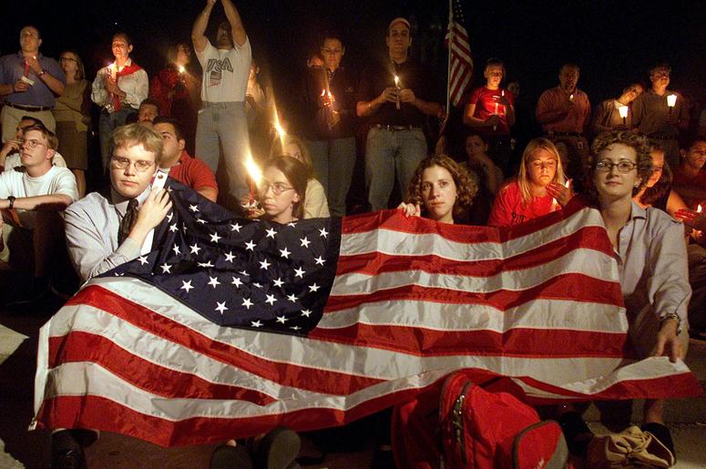 People cover themselves with an American Flag on the US Capitol grounds during a candle light vigil to remember victims who lost there life in the recent terorist attacks September 12, 2001 in Washington DC. People cover themselves with an American Flag on the US Capitol grounds during a candle light vigil to remember victims who lost there life in the recent terorist attacks September 12, 2001 in Washington DC. (Photo by Mark Wilson/Getty Images)