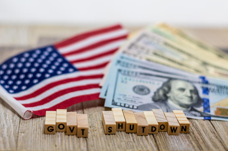 Government Shutdown USA concept with American flag and money bills on white background and wooden board Government Shutdown USA concept with American flag and money bills on white background and wooden board