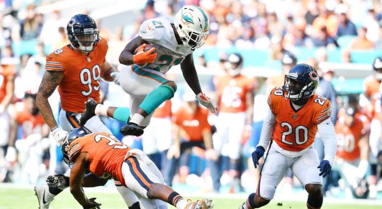 Dolphins running back Frank Gore leaps over Bears safety Adrian Amos. Dolphins running back Frank Gore leaps over Bears safety Adrian Amos.