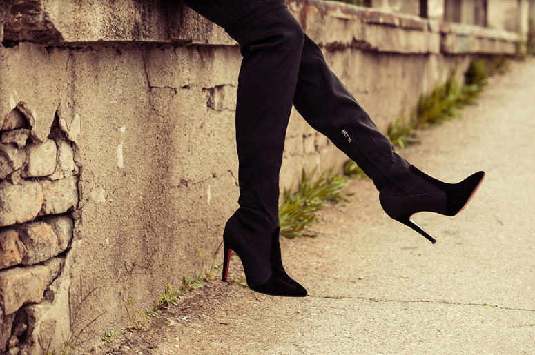 A young lady wears black high heel boots outdoors A young lady wears black high heel boots outdoors